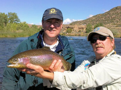 Capt. Mark Nesbit holding up a beautiful rainbow trout for a customer on a San Juan River NM fly fishing trip.