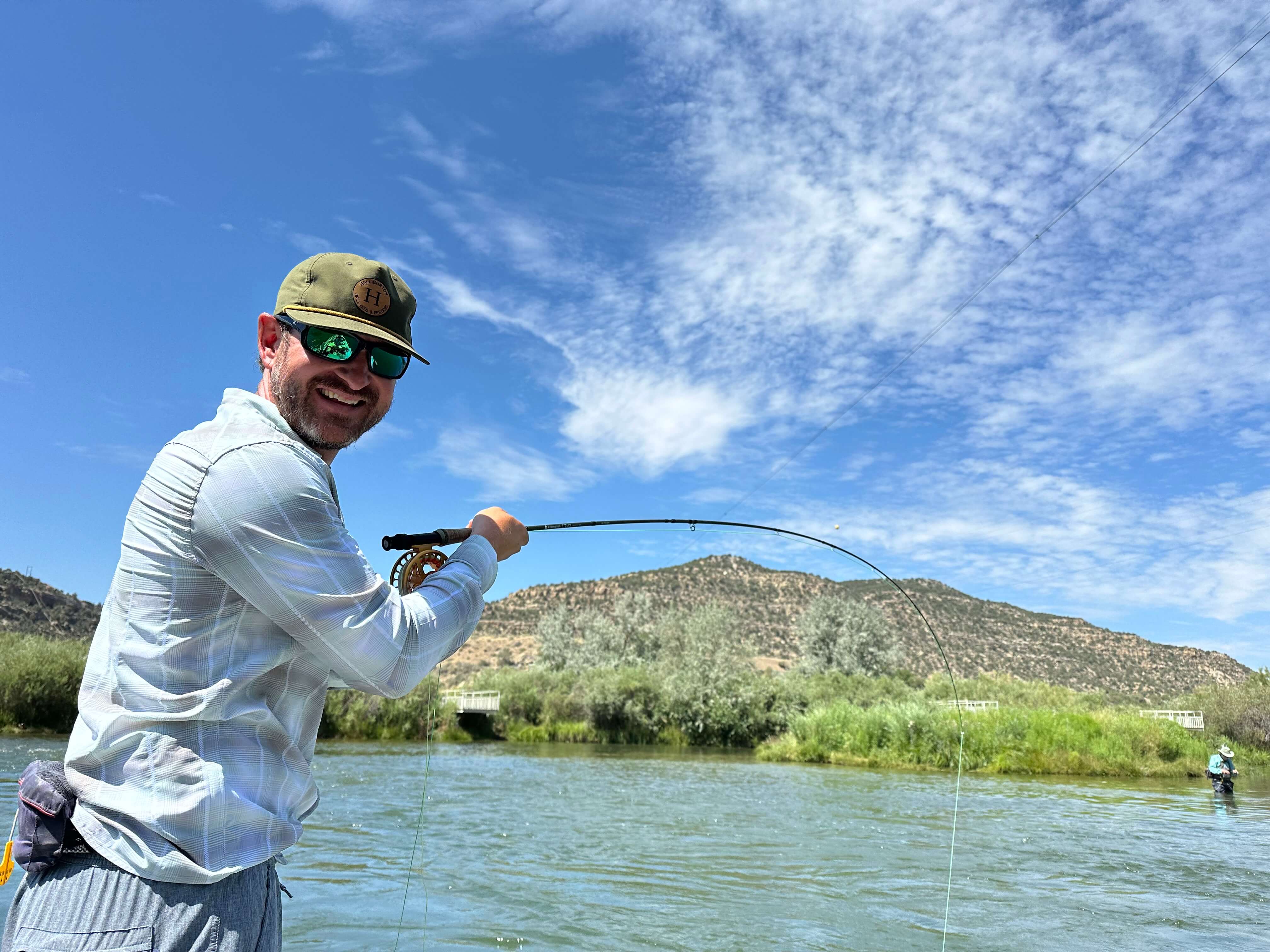 photo of charter client with a big smile and a tight line,  bent rod hooked up in the Texas Hole on the San Juan River,NM.